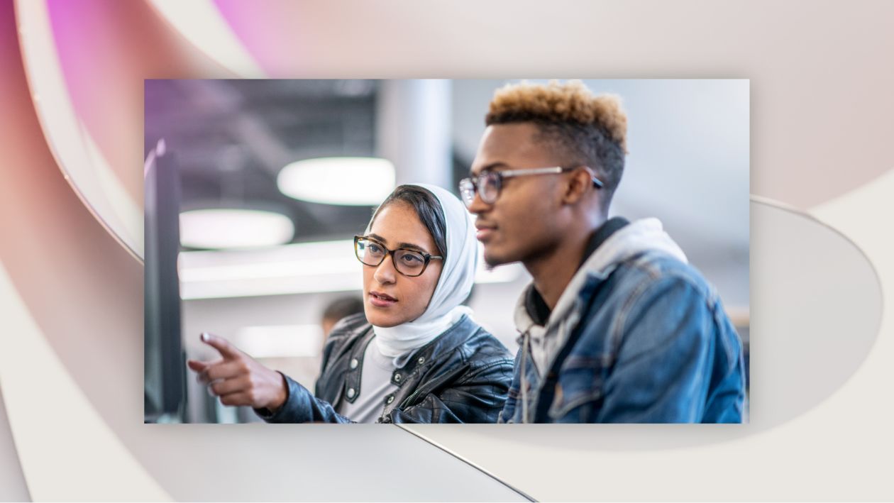 Two makers looking at a computer screen and collaborating in an office setting.
